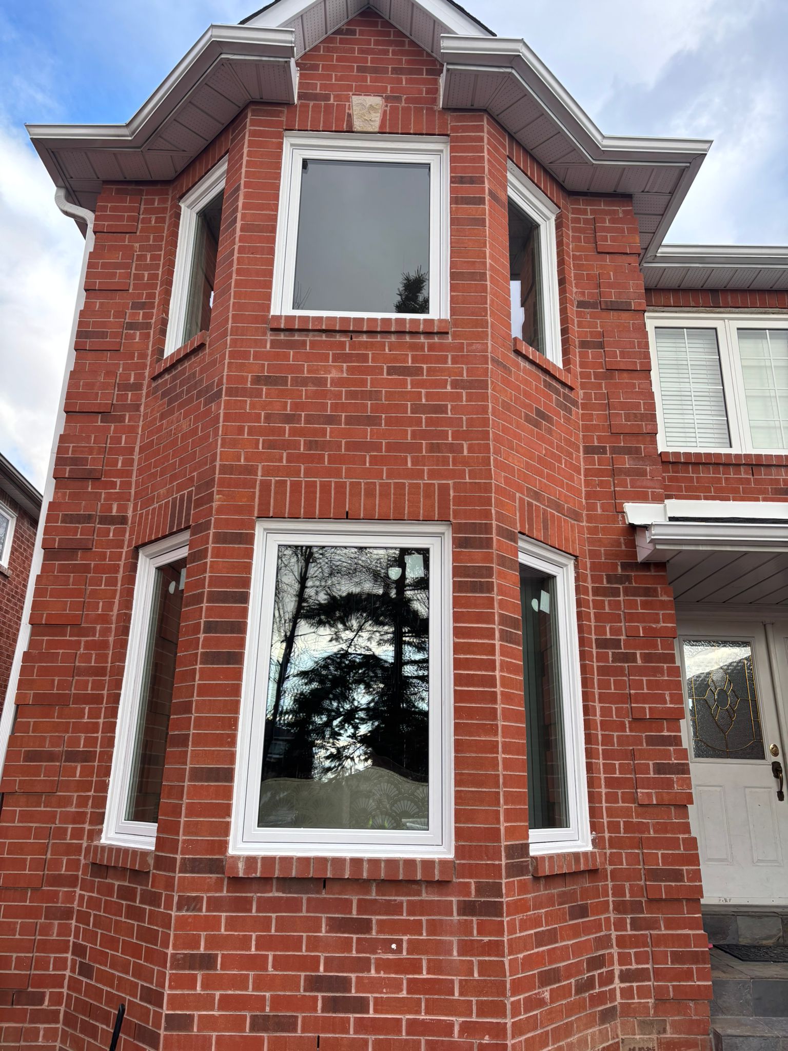 Bay window installation with three vinyl windows on brick home